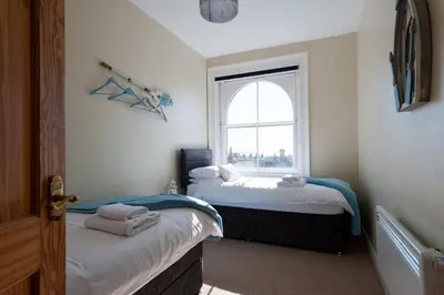 two beds in a room with a window at The Lookout Penthouse in Harwich