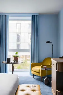a bedroom with a yellow chair and a window at Hyatt Centric Cambridge in Cambridge
