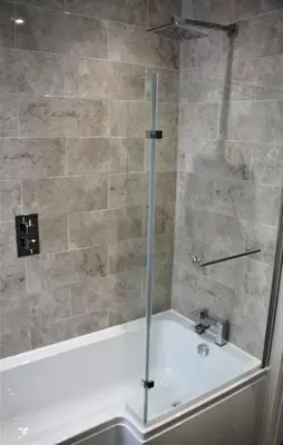 a shower with a glass door next to a tub at The Alvaros Apartment in Southend-on-Sea