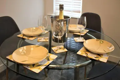 a glass table with plates and wine glasses on it at The Alvaros Apartment in Southend-on-Sea