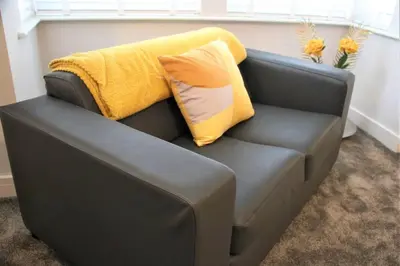 a gray couch with a yellow blanket on top of it at The Alvaros Apartment in Southend-on-Sea