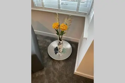 a white vase with yellow flowers on a table at The Alvaros Apartment in Southend-on-Sea