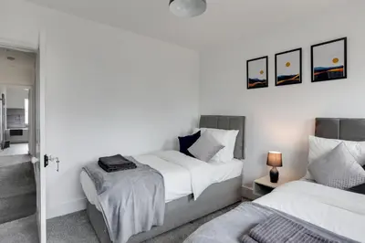 two beds in a bedroom with white walls at Spacious Three Bedroom House - Free Parking & Wifi in Chelmsford