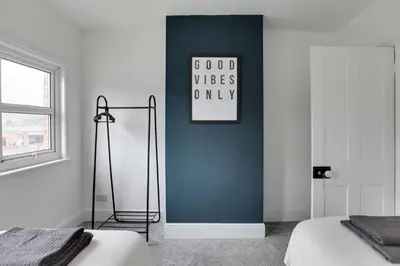 a bedroom with a blue wall with a clock on the wall at Spacious Three Bedroom House - Free Parking & Wifi in Chelmsford