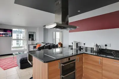a kitchen with a counter top and a living room at The Marina Penthouse in Ipswich