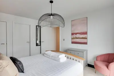 a bedroom with a bed and a pink chair at The Marina Penthouse in Ipswich