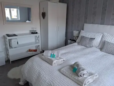 a bedroom with a white bed with towels on it at HOME from HOME GUEST HOUSE in Rochford