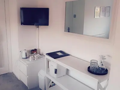 a white bathroom with a sink and a mirror at HOME from HOME GUEST HOUSE in Rochford