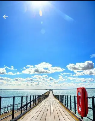 a wooden boardwalk leading into the ocean with a red mailbox at HOME from HOME GUEST HOUSE in Rochford
