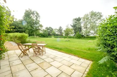 a patio with a table and chairs in a yard at The Half House in Snape