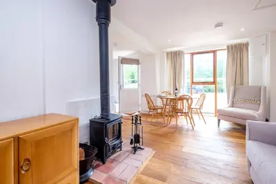 a living room with a stove and a table at The Half House in Snape