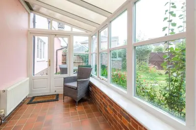 a conservatory with windows and a chair in it at Bryony Cottage, 3 bedroom house in the seaside town of Aldeburgh - Aldeburgh Coastal Cottages in Aldeburgh