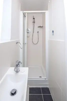 a white bathroom with a shower and a sink at Bryony Cottage, 3 bedroom house in the seaside town of Aldeburgh - Aldeburgh Coastal Cottages in Aldeburgh
