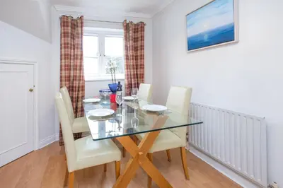 a dining room with a glass table and white chairs at Bryony Cottage, 3 bedroom house in the seaside town of Aldeburgh - Aldeburgh Coastal Cottages in Aldeburgh