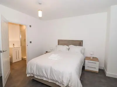 a white bedroom with a large bed with white sheets and pillows at Exning Residence in Newmarket