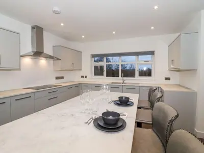 a white kitchen with a table with glasses on it at Exning Residence in Newmarket