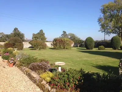 a garden with a green lawn and some bushes at Dairy Cottage in Cockley Cley