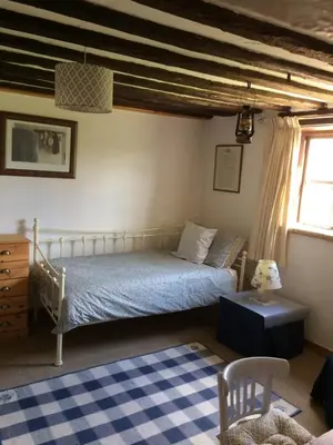 a bedroom with a bed and a blue and white rug at Dairy Cottage in Cockley Cley