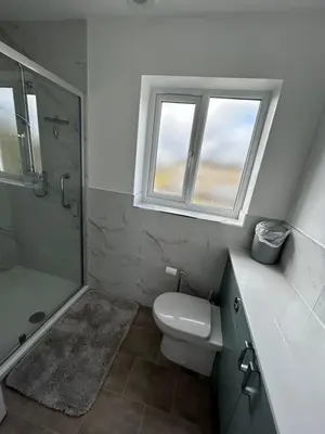 a bathroom with a toilet and a shower and a window at Magnolia House in Royston