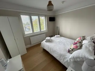 a bedroom with a white bed and two windows at Magnolia House in Royston