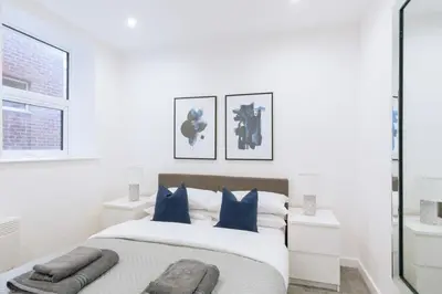 a white bedroom with a large bed with blue pillows at Budget 1 Bedroom Apartment in Central Ipswich in Ipswich