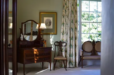 a room with a dresser and a mirror and a chair at Bressingham Hall in Bressingham