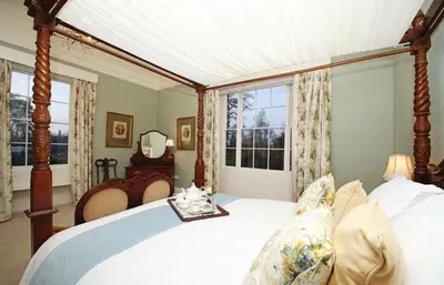 a bedroom with a canopy bed and a window at Bressingham Hall in Bressingham