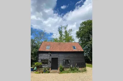 a small black house with a red roof at Gorgeous comfortable barn with huge private orchard in quiet Suffolk location in Depden