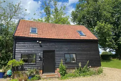 a small black house with a red roof at Gorgeous comfortable barn with huge private orchard in quiet Suffolk location in Depden