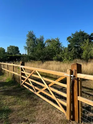a wooden fence in the middle of a field at Gorgeous comfortable barn with huge private orchard in quiet Suffolk location in Depden
