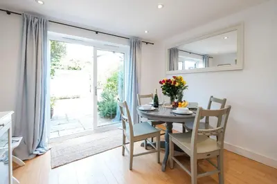 a dining room with a table and chairs and a window at 201 High Street in Aldeburgh