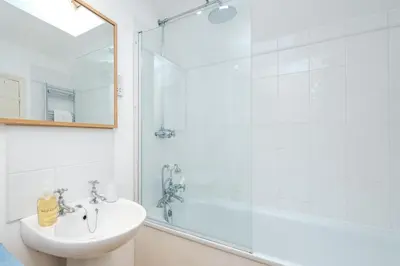 a white bathroom with a shower and a sink at 201 High Street in Aldeburgh