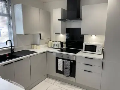a kitchen with white cabinets and a microwave at ED Colchester Accommodation with Garden View in Colchester