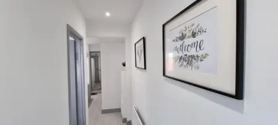 a hallway with two framed pictures on a wall at ED Colchester Accommodation with Garden View in Colchester