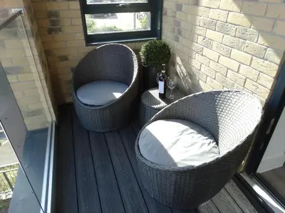 two wicker chairs sitting on a deck with a window at Old Station Apartments in Cambridge