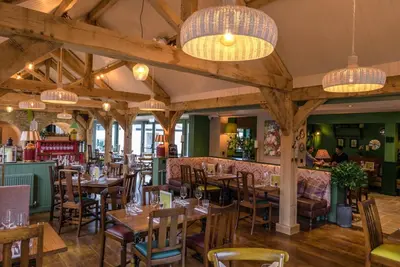a restaurant with wooden tables and chairs and chandeliers at Old Station Apartments in Cambridge