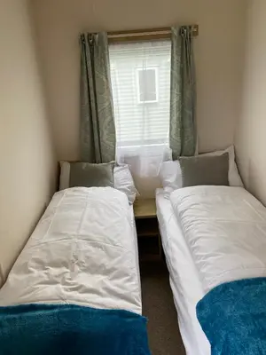two beds in a small room with a window at 5 mins walk to beach. 3 bedroom caravan. Sleeps 8 in Clacton-on-Sea