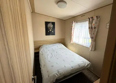 a small bed in a small room with a window at St Osyth- Sleeps8-freeparking-wifi-holidaypark in Clacton-on-Sea