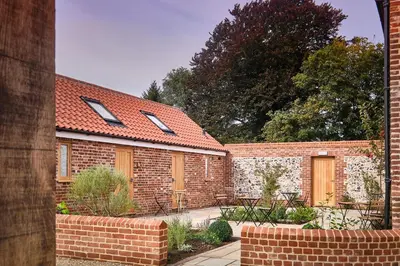 a brick building with two doors and a courtyard at Guinness Arms in Icklingham