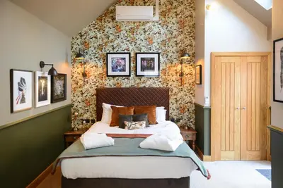 a bedroom with a bed and a wall with flowers at Guinness Arms in Icklingham