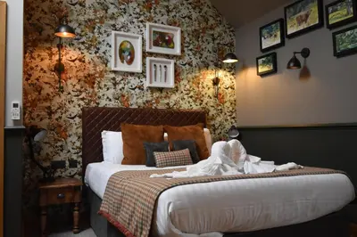 a bedroom with a bed and a wall covered in pictures at Guinness Arms in Icklingham