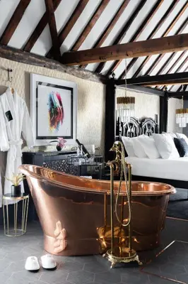 a bathroom with a copper tub and a bed at Staycations Maldon in Maldon
