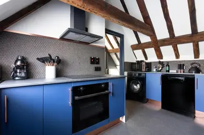 a kitchen with blue cabinets and a black dishwasher at Staycations Maldon in Maldon