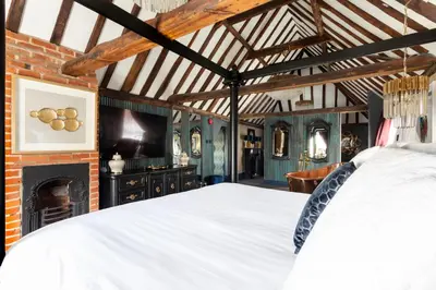 a bedroom with a white bed and a fireplace at Staycations Maldon in Maldon