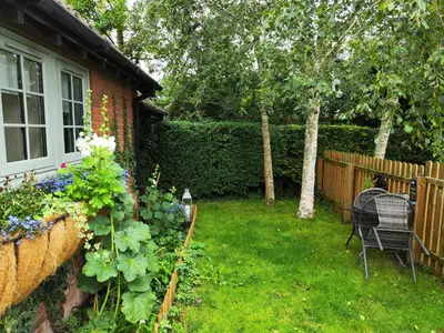 a yard with a fence and a chair and flowers at Hunters Lodge in Norwich