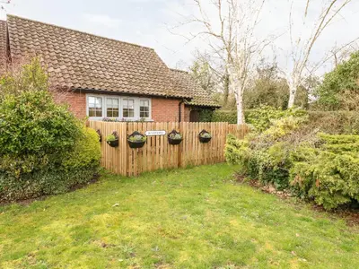a fence in front of a house with plants at Hunters Lodge in Norwich