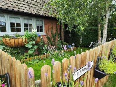 a wooden fence in front of a house with flowers at Hunters Lodge in Norwich