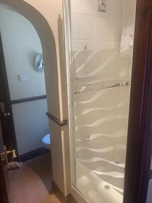 a shower with a glass door in a bathroom at Burnt Mill Cottage in Burnham on Crouch