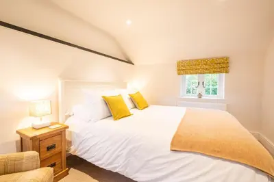 a bedroom with a large white bed with yellow pillows at 1 Chantry Cottage in Tunstall