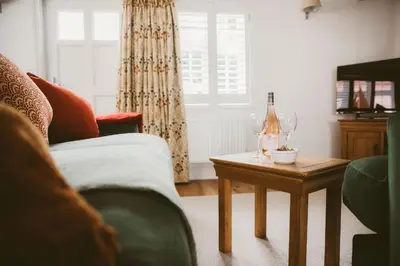 a living room with a couch and a table with wine glasses at 1 Chantry Cottage in Tunstall
